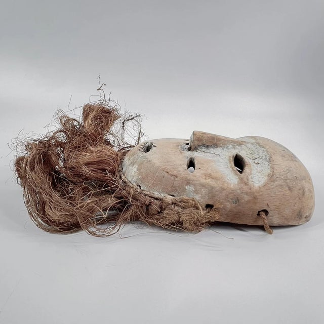 Lega masks, wooden and featuring elongated faces with a central ridge, almond-shaped eyes, and symbolic geometric...