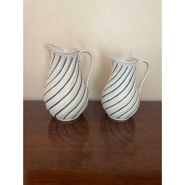 These two pitchers are have beautiful bas relief vines striped diagonally down the sides while interspersed with teal...