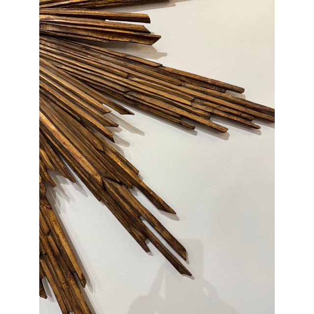 Italian vintage starburst mirror. Gold gilt arms with black frame around the mirror. All wood. 63”dia 49-222