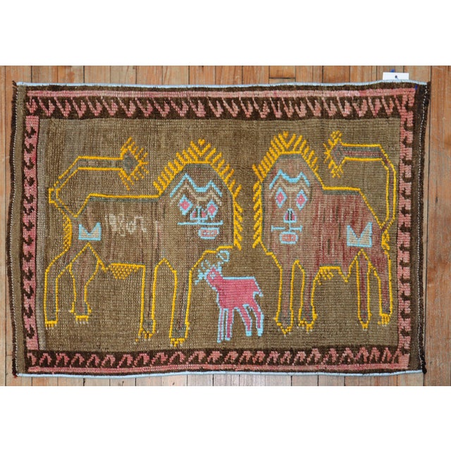 A late 20th century Turkish rug depicting 2 lions outlined in yellow and a pink sheep outlined in light blue on a brown...