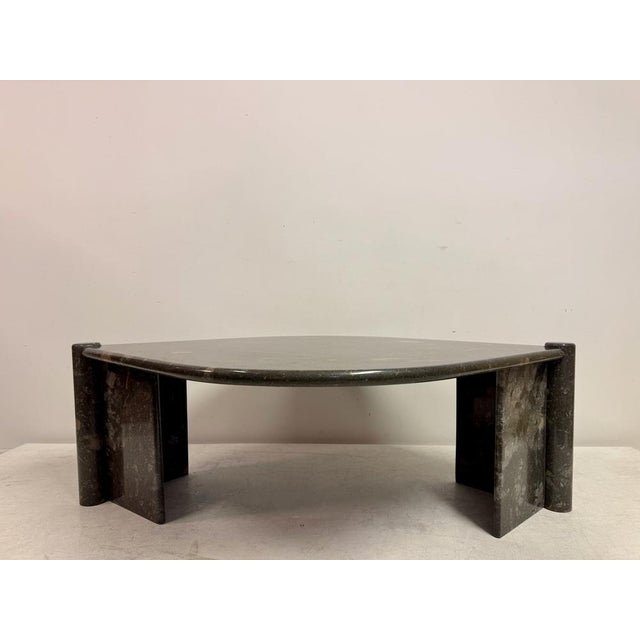 A sculptural low table in dark fossil stone or marble, dating to the late 20th century. The organically shaped top is...