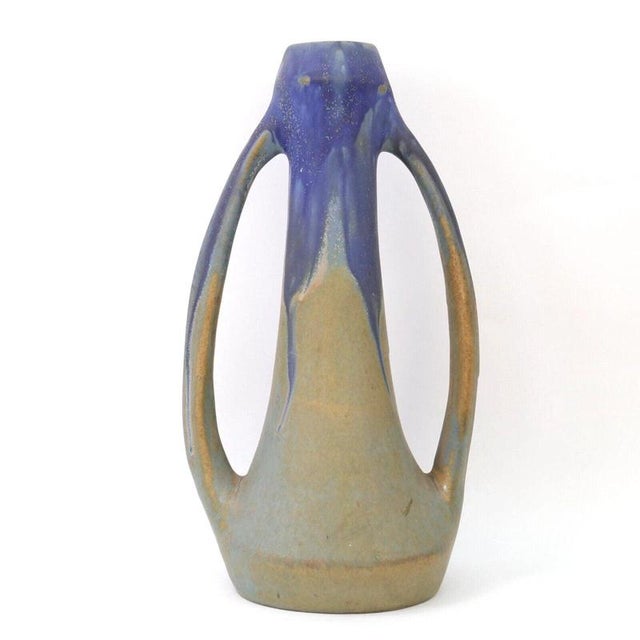 Two elongated loop handles frame the slender, tapering body of this French art pottery vase, sweeping from just below the...