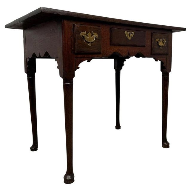 A handsome 18th-century English side table, finely crafted from solid oak and distinguished by its elegant turned legs,...