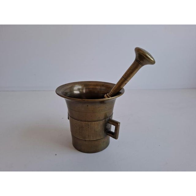 Elegant antique brass mortar and pestle in an art deco-inspired geometric design, originating from czechoslovakia. The...