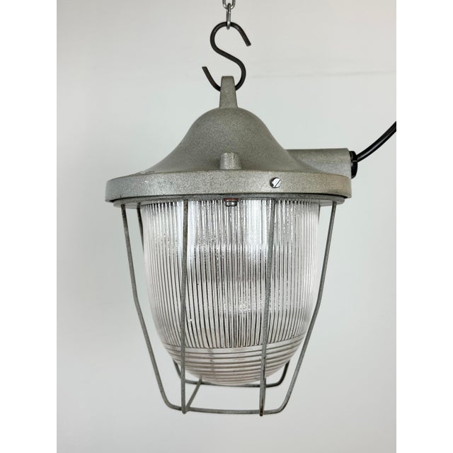 Light grey industrial lamp made by Polam Gdansk in Poland during the 1960s. It features a cast aluminium body, an iron...