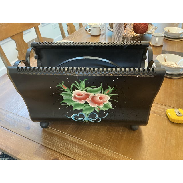 A charming vintage hand-painted metal tôleware magazine rack/caddy finished in matte black. Features a hand-painted floral...