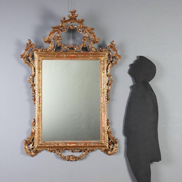 Carved and gilded wood mirror from early 20th century Italy, representing a refined example of decorative craftsmanship....