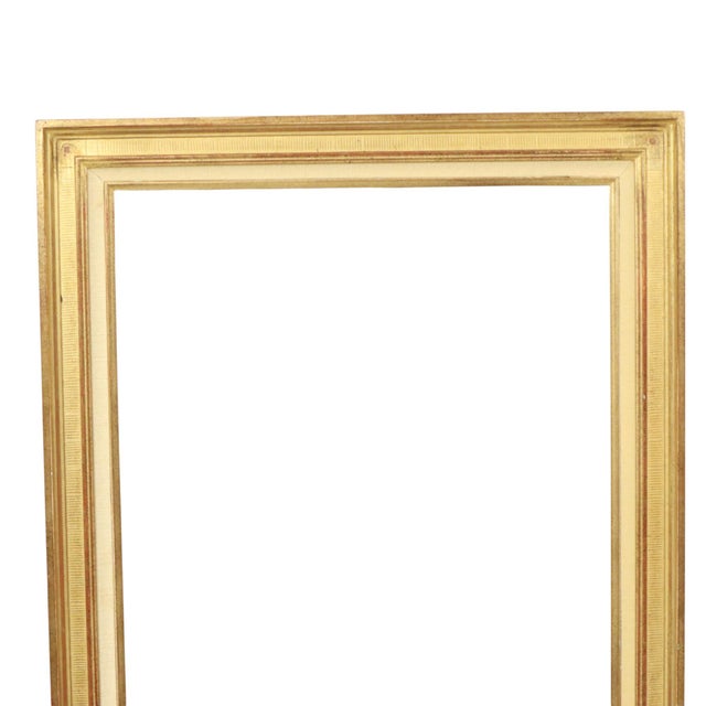 A sleek, vintage gold-tone frame made of solid wood and plaster; featuring a classic style with a linear pattern running...