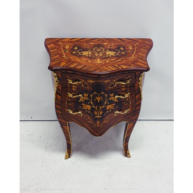 Exceptional marquetry chest of drawers with refined wooden inlay and elegant gold-colored fittings. This elegant Louis XV-...