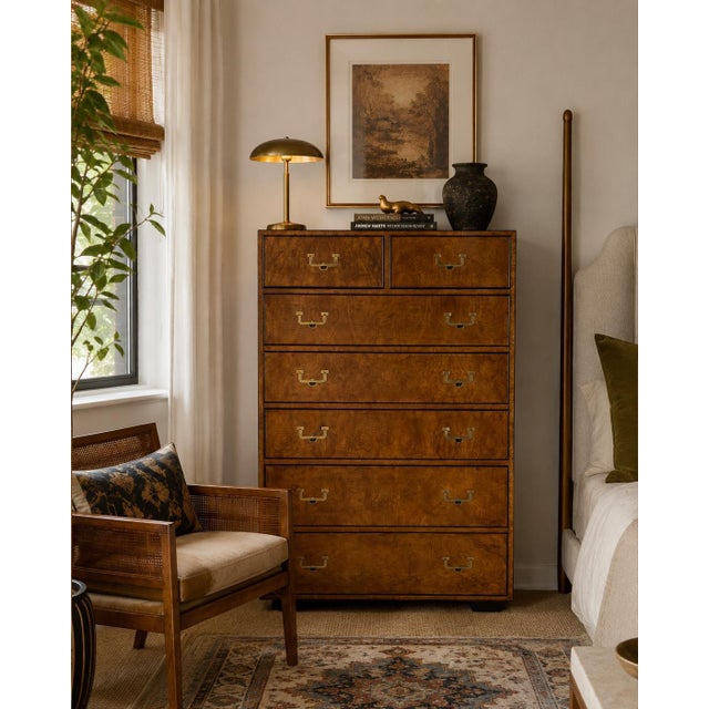 A beautifully crafted 1970s John Widdicomb Campaign-style highboy dresser featuring striking burled wood veneers with rich...