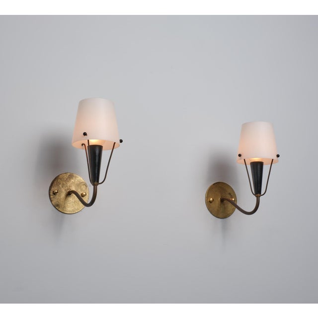 Pair of Italian wall sconces from the 1950s, made of brass and solid opaline glass, exemplifying the refined elegance of...