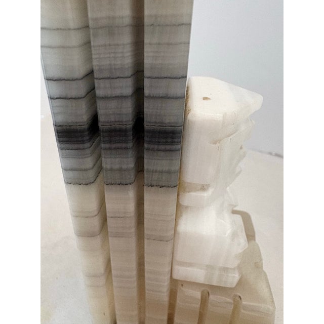 A striking pair of mid-century carved onyx marble bookends, featuring stylized Aztec-inspired figural busts set against...