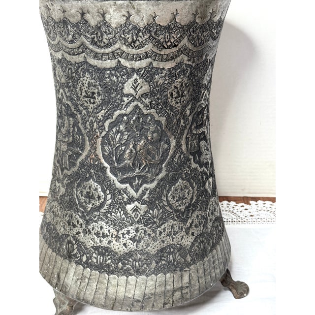 This is an antique Persian silver-washed copper can from the late 19th century. It has beautiful hammered engraving with...