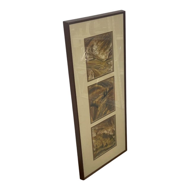 Framed batik artwork by artist Louise "Lou" Wilson, composed of three individual nature scenes arranged vertically within...