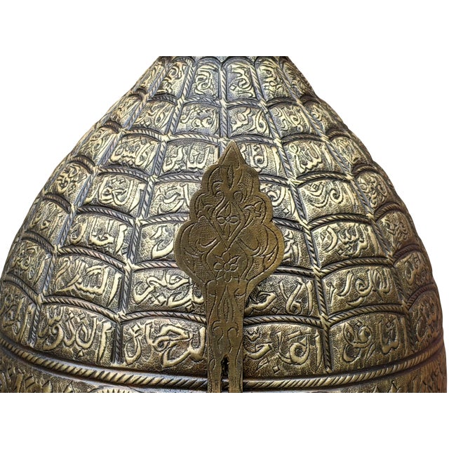 The Asma-ul Husna Helm A true collector's artifact, this heavy brass turban helmet is defined by its architectural...