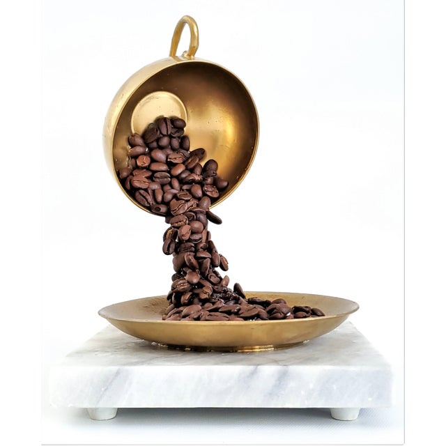 Offering a unique Pop Art sculpture of a coffee cup with coffee beans, circa 1980s. It is mounted on a white marble base...