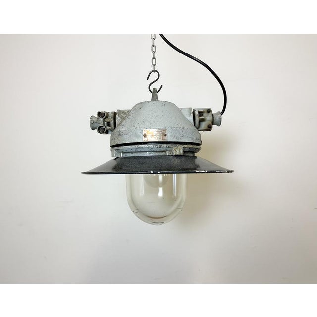 Grey industrial lamp with massive protective glass bulb made by Elektrosvit in former Czechoslovakia during the 1970s.It...