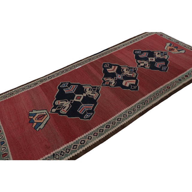 Handwoven in wool, circa 1950-1960, this 4x9 Afghani tribal Kilim rug, features an open red field and midnight blue...
