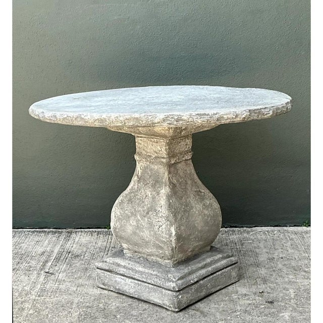 Built from solid cast cement, this vintage pedestal table presents a commanding architectural silhouette defined by raw,...