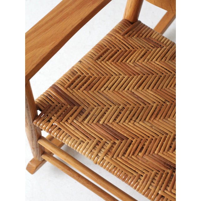 This antique rocking chair features a handcrafted slat back and a woven herringbone seat. Ideal for a cozy reading nook,...