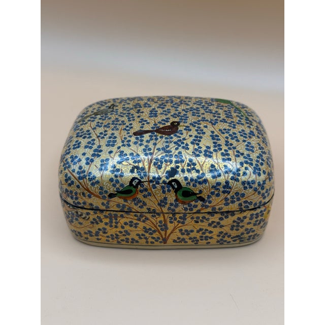 Charming vintage Kashmiri papier-mâché decorative box featuring an intricate hand-painted design of stylized birds perched...