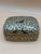 Charming vintage Kashmiri papier-mâché decorative box featuring an intricate hand-painted design of stylized birds perched...