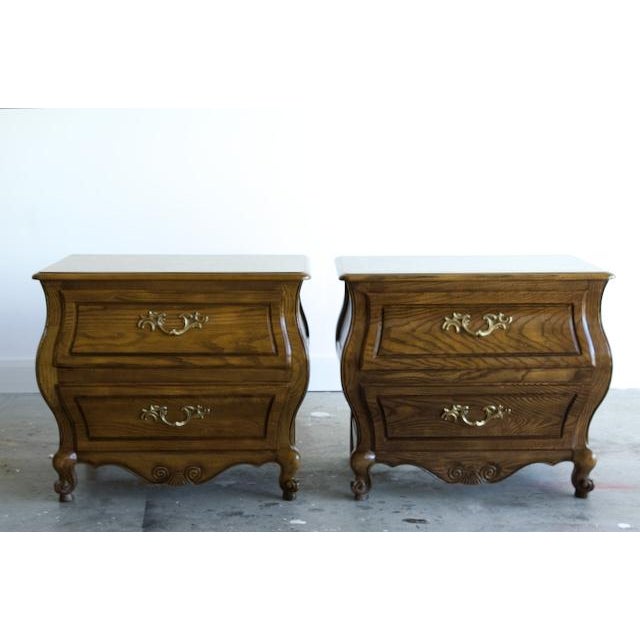 Pair of French bombé nightstands in solid oak by Baker Furniture, each with a beautifully figured burl top panel framed in...