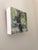 This artwork captures a serene forest edge, where lush greenery meets the textured bark of a tree. The vibrant brushwork...