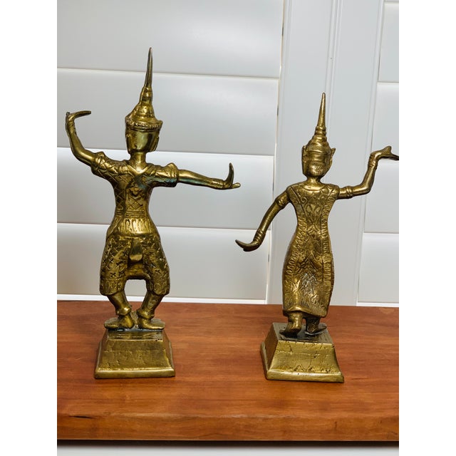 A matched pair of vintage brass statues depicting Thai dancers in traditional ceremonial poses. These figures capture the...