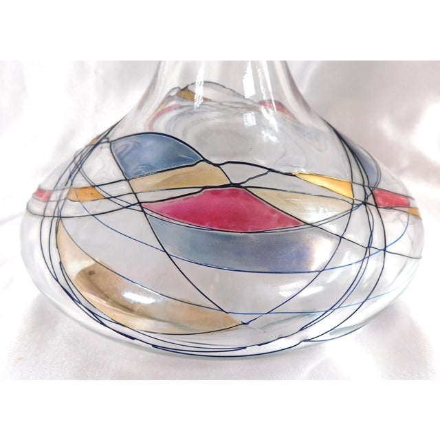 This is a clear glass ships decanter with a stopper. The bottom of the decanter has a random design in black raised paint....