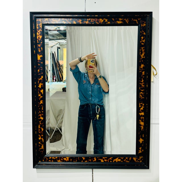 A sophisticated John-Richard (Mississippi) wall mirror featuring a richly detailed faux tortoise shell frame bordered by...