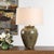 The Olisa Table Lamp Showcases A Timeless Ceramic Urn Base Finished In Shades Of Green, Blue-green, And Earthy Browns,...