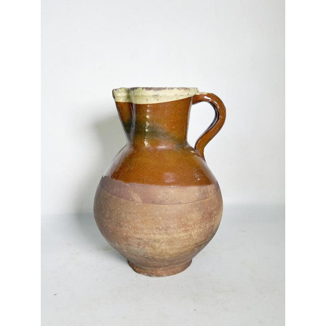 A ceramic pitcher, France, 1960s, with rustic and authentic charm. Made of terracotta with a nuanced warm brown glaze, it...
