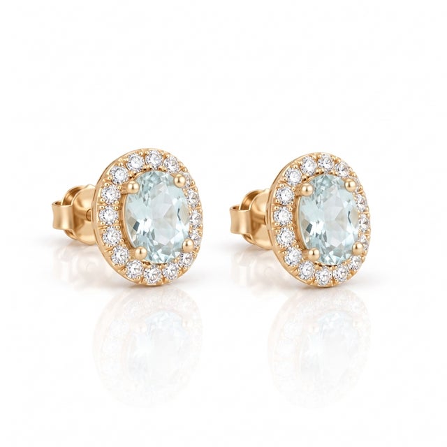 Enhance your style with the delicate shimmer of these extreme light aquamarine oval halo stud earrings. Featuring a pale,...