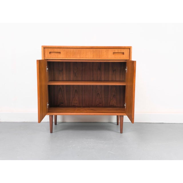 High-quality teak cabinet with two hinged doors and one drawer, each featuring stylish recessed handles. Inside, there's...