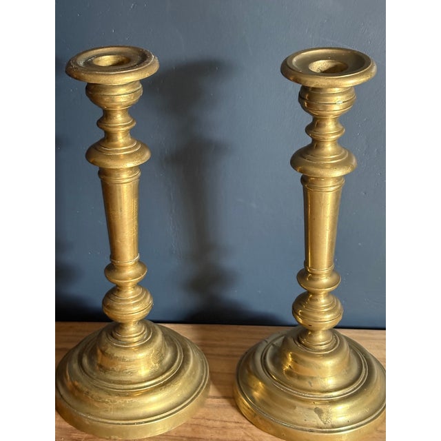 A pair of French brass candlesticks, 19th century. Turned baluster form with a tapered column stem, knopped collar, and a...