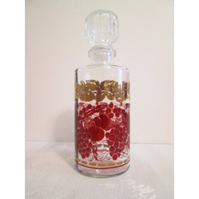 Pretty vintage French clear glass decanter featuring a fruit vine-motif in a deep shade of burgundy around perimeter with...