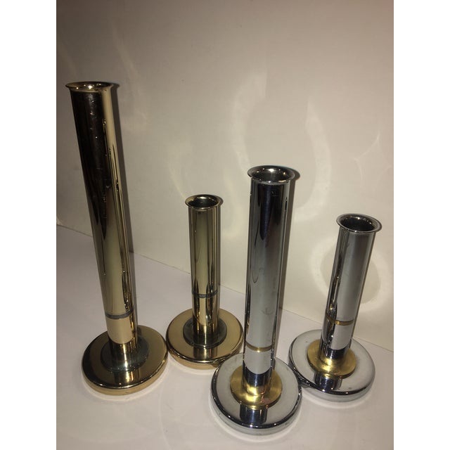 A set of four mid century modern candle stick holders. Features heavy brass, chrome, and 24 carat gold plated cylindrical...