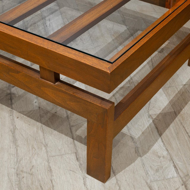 ABOUT This Mid-Century Modern coffee table is a standout piece of expert woodworking. Crafted from solid walnut, it relies...