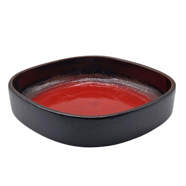 A square ceramic tray or bowl, featuring a deep red ‘Fat Lava’ interior glaze and a dark brown gradient rim, typical of...