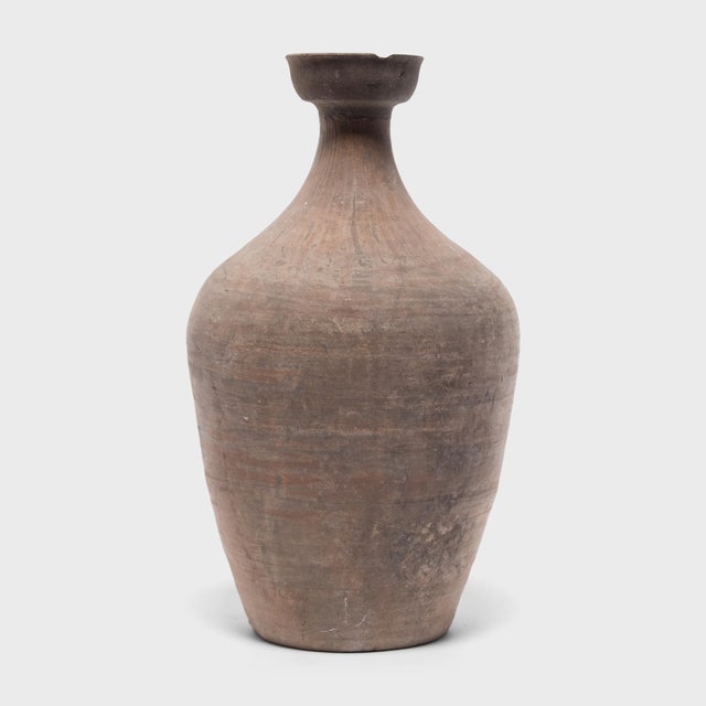This ceramic jar from China's Shandong province has a bottle-neck shape meant for storing vinegar or wine made from rice...