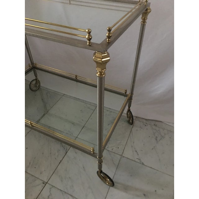 Stunning vintage brass and polished metal bar cart in the Maison Jansen neoclassical style . Two glass shelves with brass...