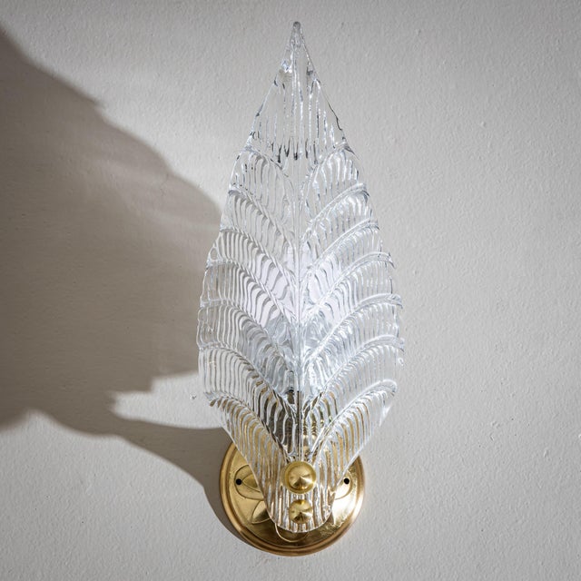Pair of wall lamps with lampshades in the form of stylized leaves made of clear glass. The wall mounts are made of bronze.