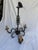 Three-arm black wrought iron chandelier with dense scrollwork on arms and center column; scalloped bobeches, drip candle...
