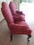 Pair of traditional burgundy Queen Anne-style upholstered armchairs featuring dark wood cabriolet legs and a rose/crimson...