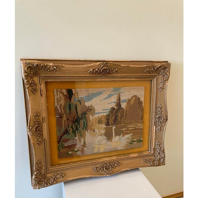 Vintage hand-stitched needlepoint landscape depicting a serene lake scene with swans gliding across the water beneath a...