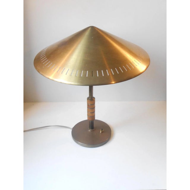 This model B146 patinated brass table or desk lamp has a partially perforated cone-shaped shade and a stem with mahogany...