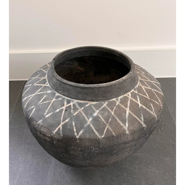 Chinese Banshan style unglazed earthenware jar with a tapered body, textured sides and painted crosshatch markings at the...