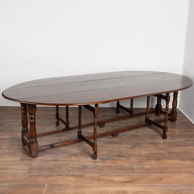 Early 20th century English wake gateleg dining table crafted from dark English oak. This impressive oval table features...
