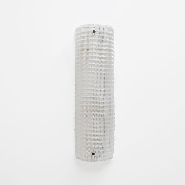 A pair of textured murano glass wall sconces. The glass, featuring a ribbed texture and curved design, creates a striking...